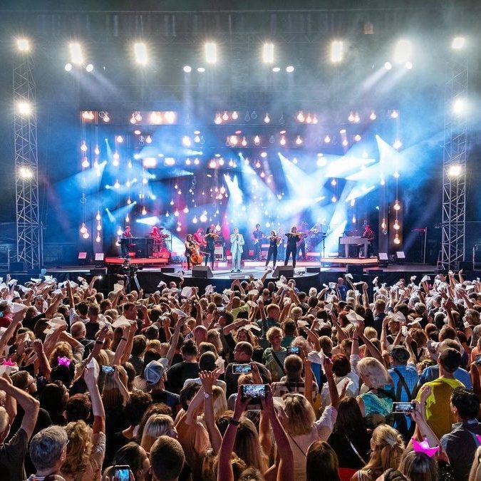 Ein voller Konzertsaal mit Menschen, die eine Band auf der Bühne sehen.