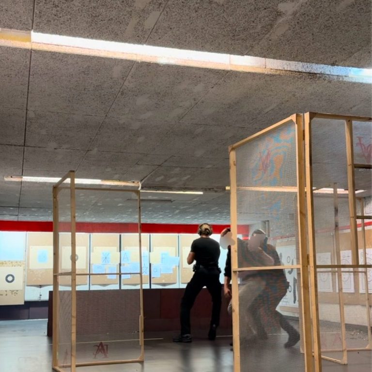 Polizisten in einer Übungen, umgeben von Holzrahmen und einem schlichten, modernen Raum.