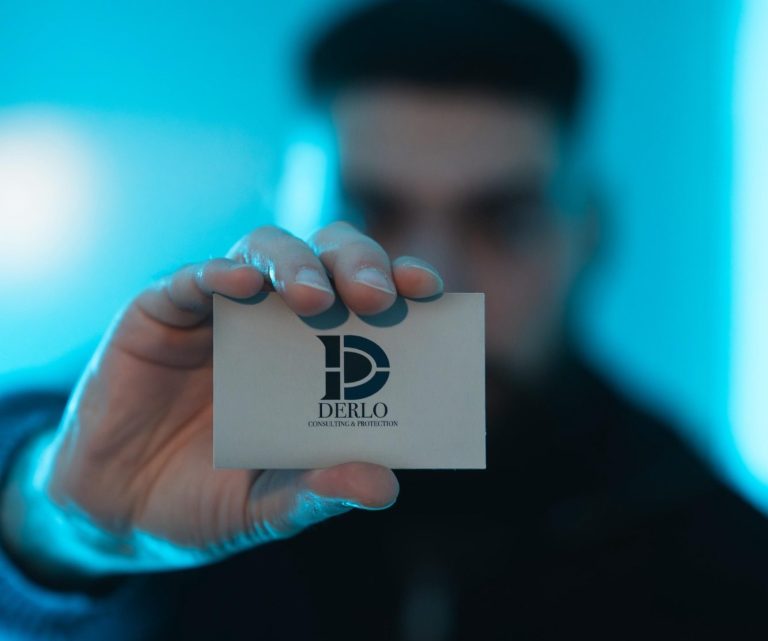 Eine Person hält eine Visitenkarte mit einem Logo in einem blauen Licht.