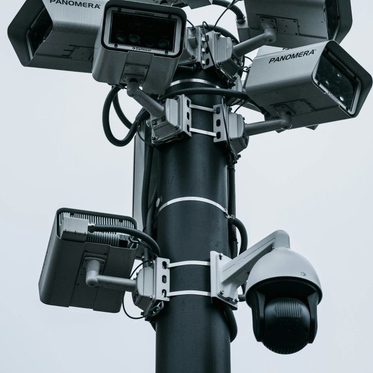 Mehrere Überwachungskameras an einem schwarzen Pfosten montiert.