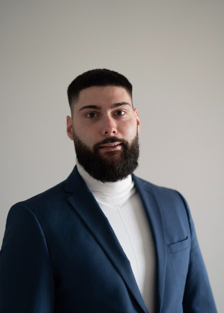 Mann mit Bart in Anzug und Rollkragenpullover, schaut direkt in die Kamera.