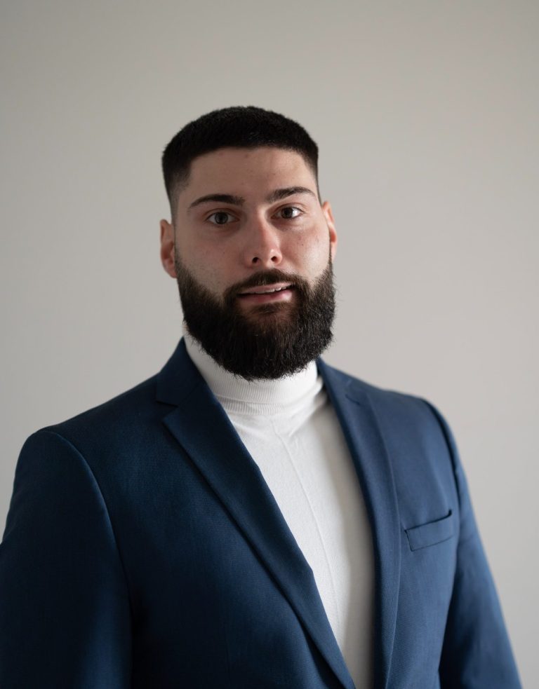 Ein Mann mit Bart, in Anzug und Krawatte, schaut direkt in die Kamera, als Sicherheitsberater.