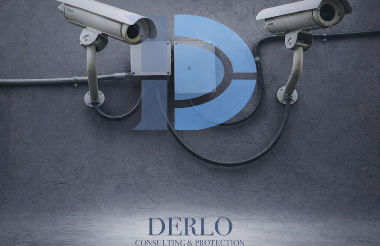 Sicherheitskamera über dem Schriftzug „DERLO“ auf einer grauen Wand.